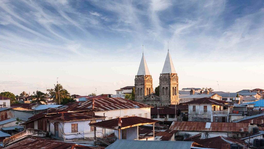 Aerial view of Stone Town, Zanzibar at sunset showcasing historic buildings, waterfront, dhows, and Forodhani Gardens